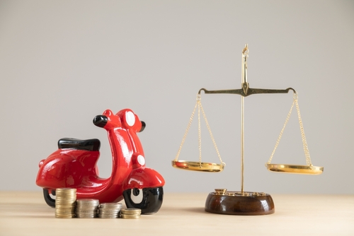A toy motorcylce near a judicial balancing scale to represent a motorcycle accident lawyer helping a victim get compensation.