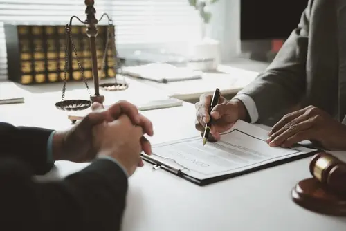 A personal injury lawyer speaking wiht a client about their personal injury claim while doing paperwork.