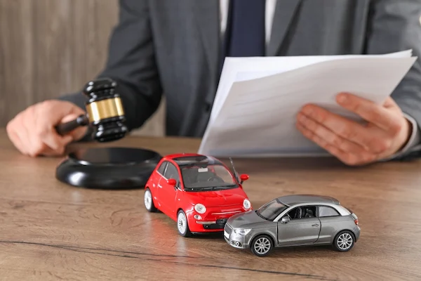 A car accident attorney works on a case at a desk with two model cars.