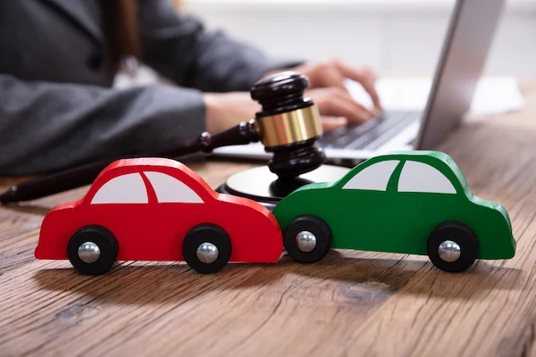 A Clemson rideshare accident lawyer works at a desk with two small cars.