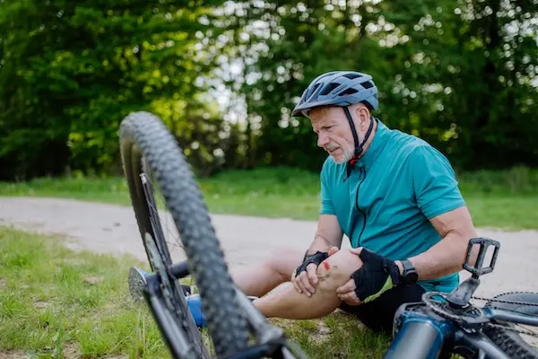 A male cyclist with a hurt knee to represent someone who may need a bicycle accident lawyer .